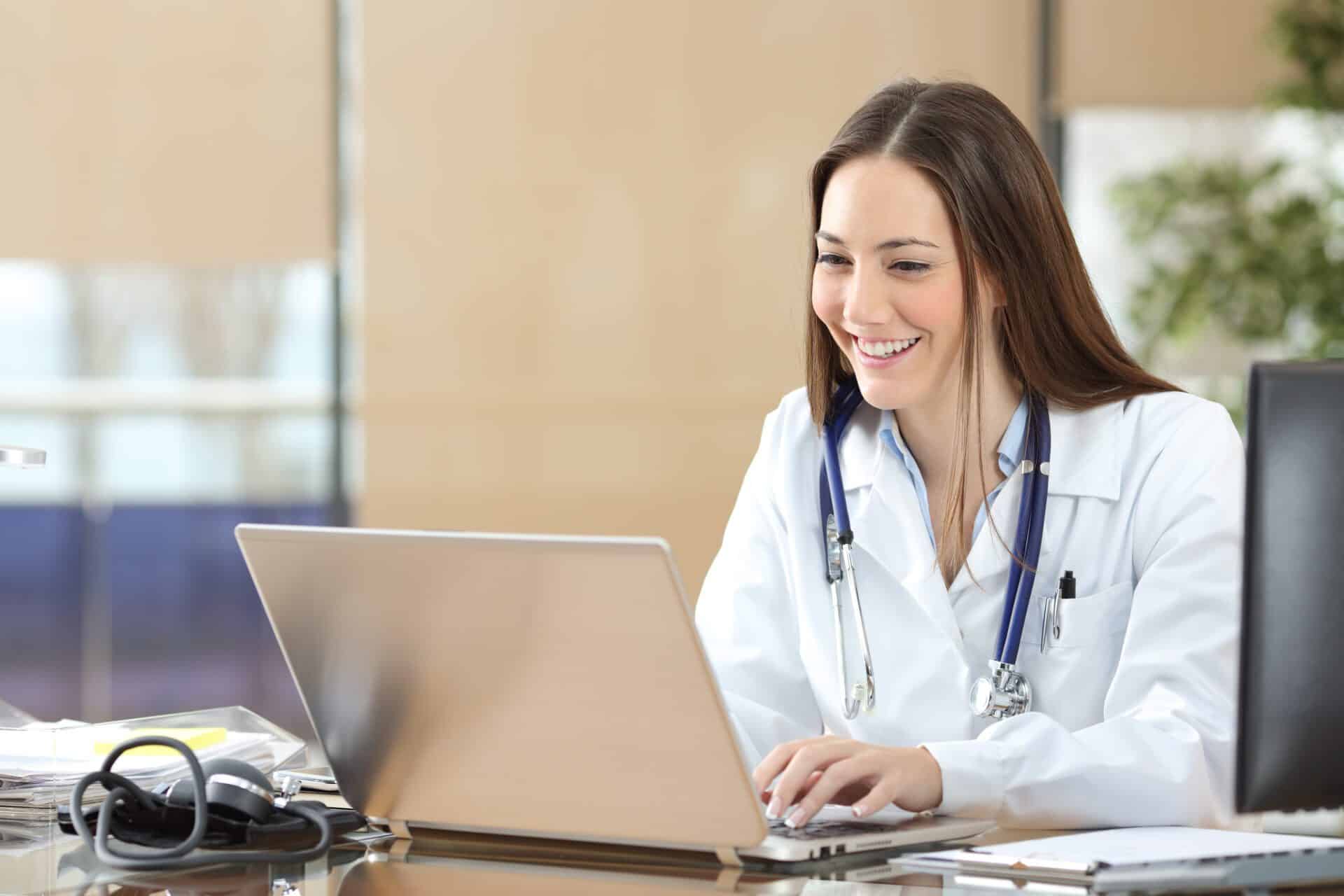 Happy doctor using a laptop at consultation Happy doctor