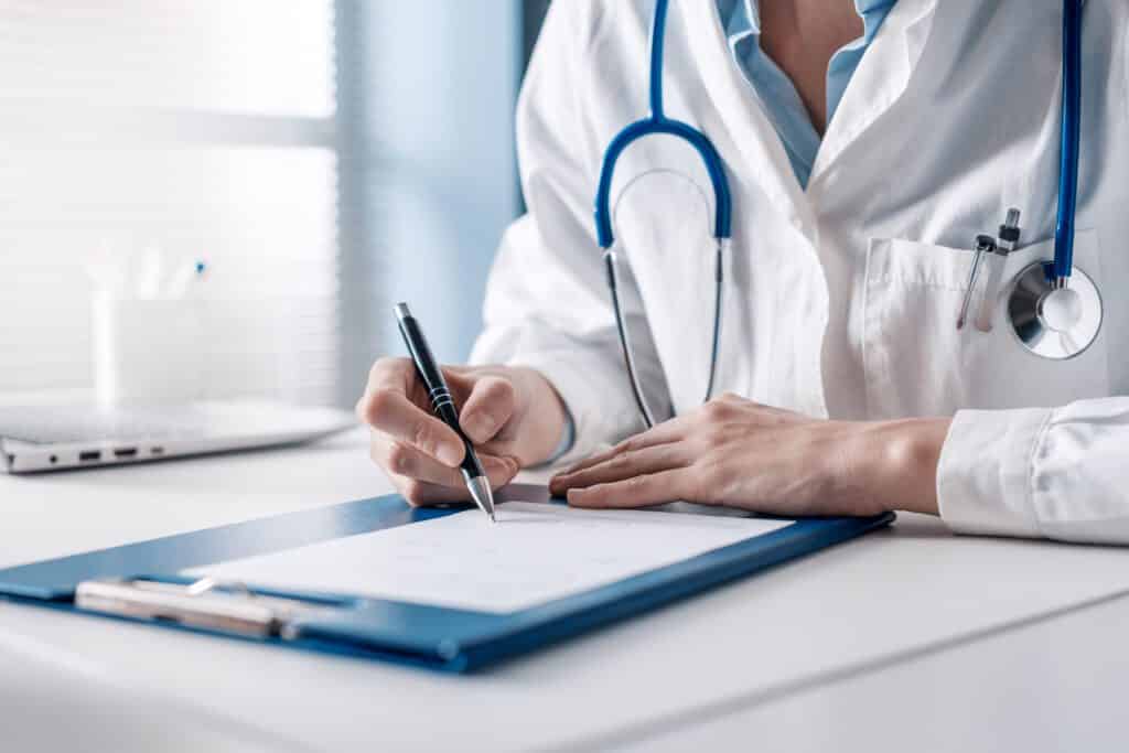 Doctor sitting at desk and writing a prescription for her patient